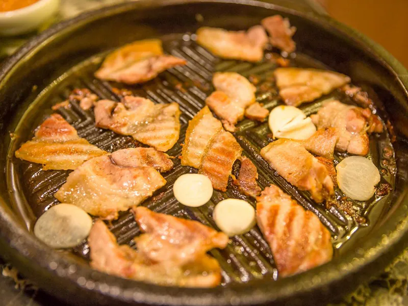 Sizzling pork belly grilled with fresh garlic slices at KTOP Korean BBQ and Hot Pot, an Asian Restaurant in Longview